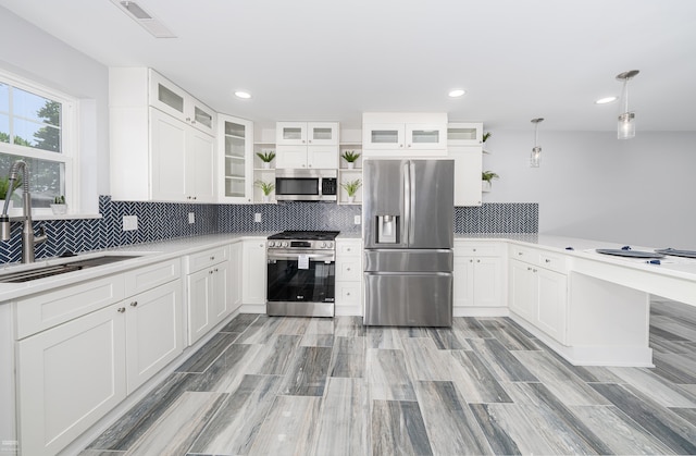 kitchen featuring appliances with stainless steel finishes, decorative light fixtures, and white cabinetry