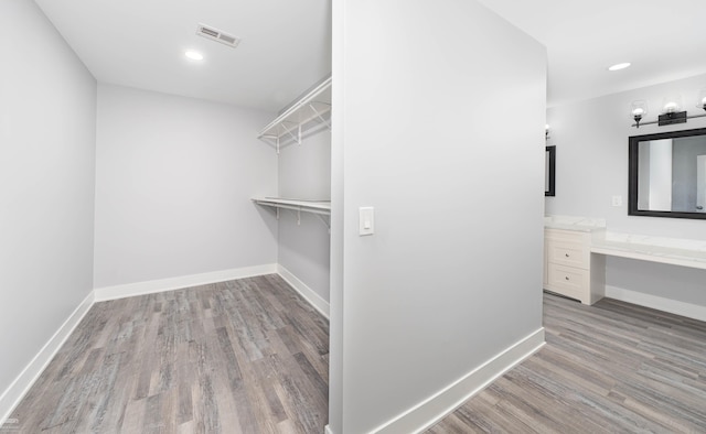 walk in closet featuring light hardwood / wood-style flooring and built in desk