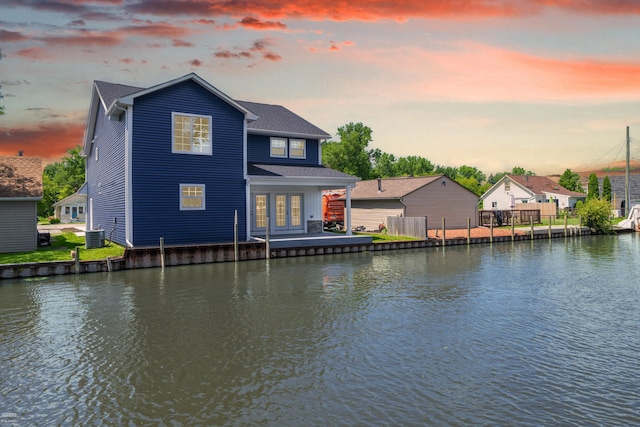 back house at dusk with cooling unit, a water view, and french doors