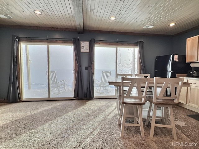 carpeted dining room featuring beam ceiling and wooden ceiling