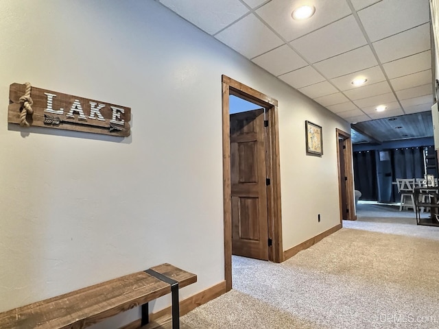 hallway featuring carpet flooring and a drop ceiling