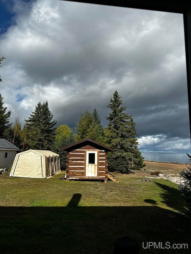 view of outbuilding featuring a water view and a lawn