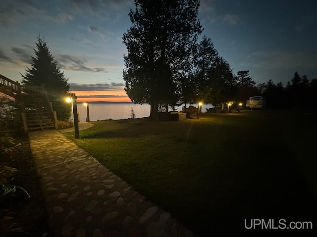 yard at dusk featuring a water view