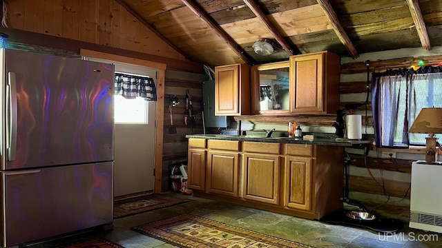 kitchen featuring lofted ceiling with beams, stainless steel refrigerator, wooden walls, and wood ceiling