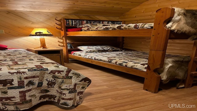 bedroom with wood walls, hardwood / wood-style floors, wooden ceiling, and vaulted ceiling