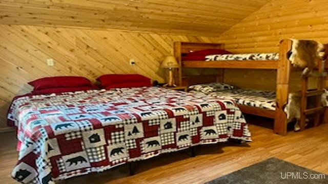 bedroom featuring wooden walls, wood ceiling, lofted ceiling, and hardwood / wood-style flooring