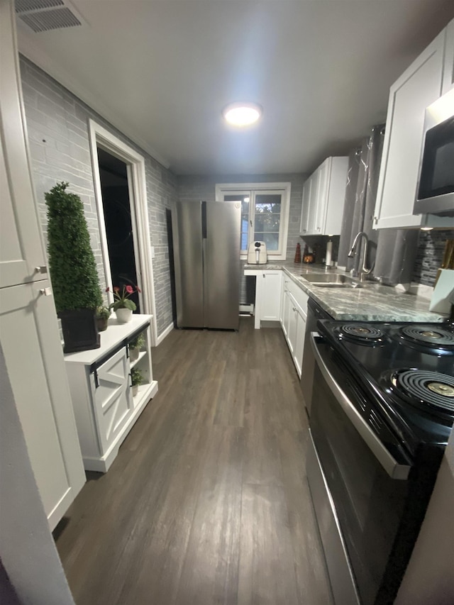 kitchen featuring dark wood finished floors, visible vents, a sink, white cabinets, and appliances with stainless steel finishes