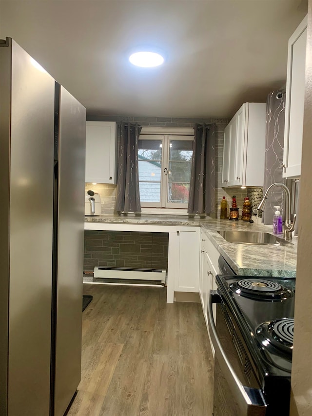 kitchen with electric range, white cabinetry, sink, and stainless steel refrigerator