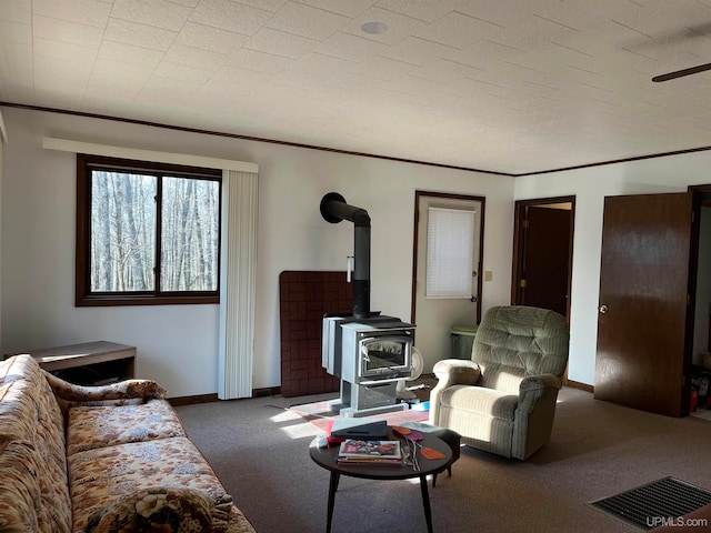 living room featuring a wood stove, ceiling fan, and dark carpet