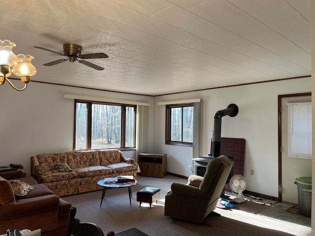 living room featuring ceiling fan with notable chandelier, light colored carpet, a wood stove, and crown molding