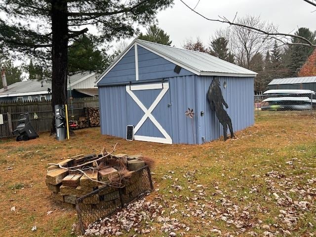 view of outbuilding with a yard and an outdoor fire pit