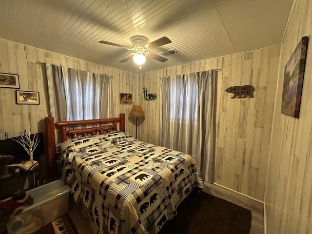 bedroom featuring ceiling fan and wooden walls