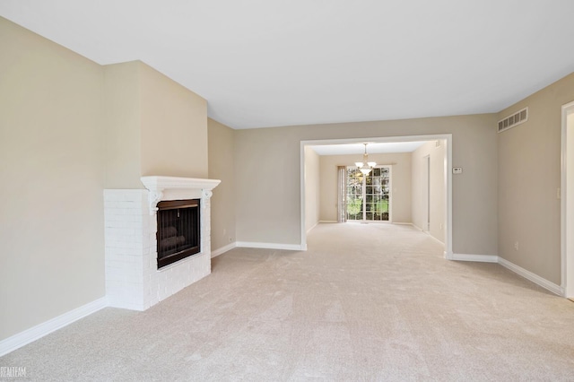 unfurnished living room with a chandelier, light colored carpet, and a brick fireplace