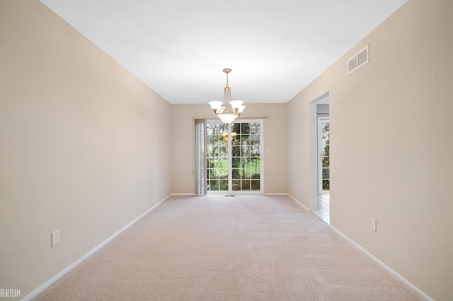 carpeted empty room featuring an inviting chandelier