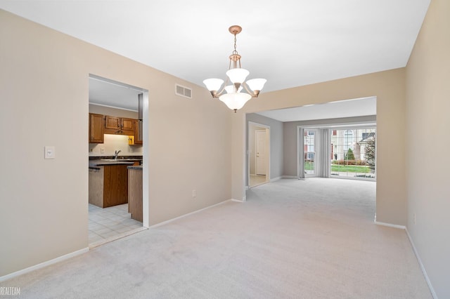 carpeted empty room with a chandelier and sink