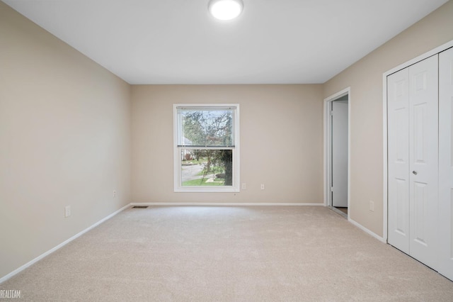 unfurnished bedroom with light carpet and a closet