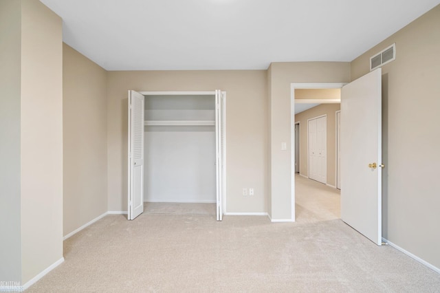 unfurnished bedroom with light colored carpet and a closet