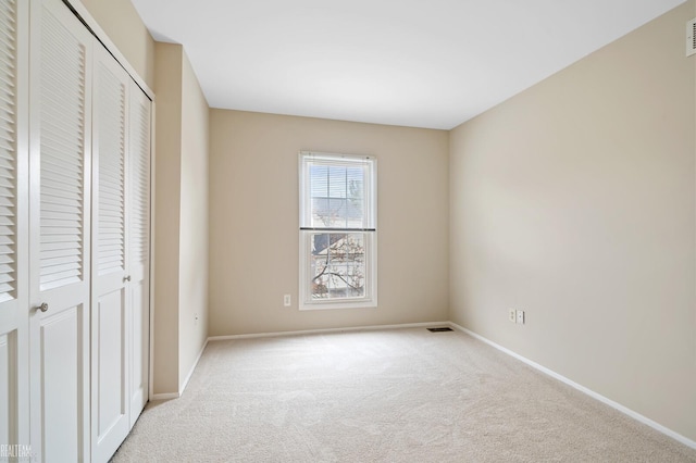 unfurnished bedroom featuring light carpet and a closet