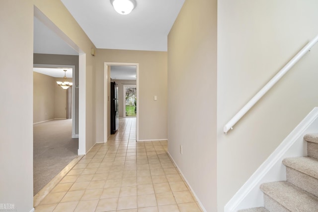 corridor with a notable chandelier and light colored carpet