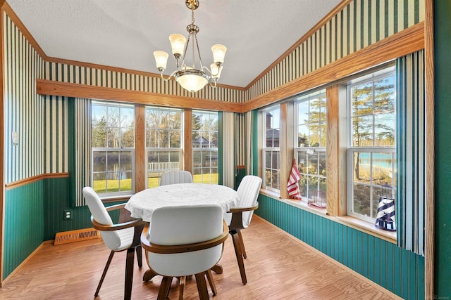 dining area with lofted ceiling, light wood-type flooring, a textured ceiling, and a chandelier