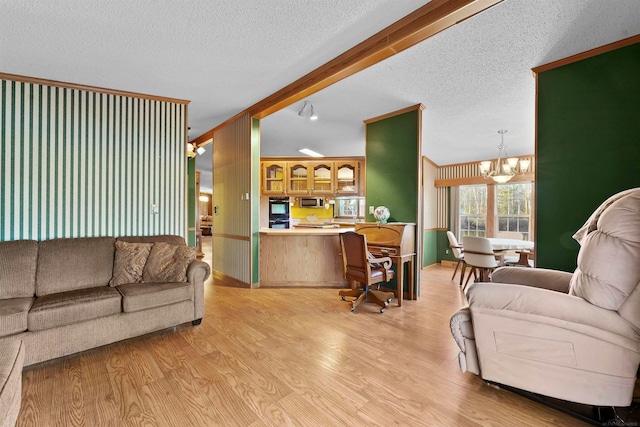 living room with a textured ceiling, vaulted ceiling with beams, light hardwood / wood-style flooring, and an inviting chandelier