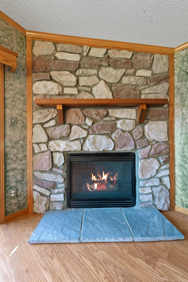 interior details featuring crown molding, a fireplace, a textured ceiling, and hardwood / wood-style flooring