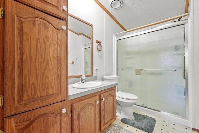 bathroom with a textured ceiling, toilet, vanity, a shower with shower door, and ornamental molding