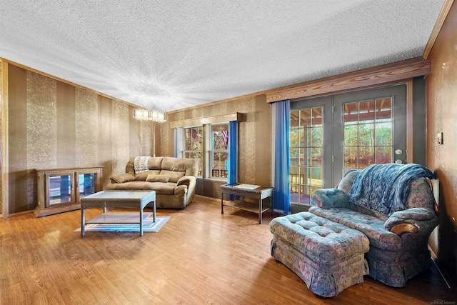 sitting room featuring crown molding, wood-type flooring, a textured ceiling, and an inviting chandelier