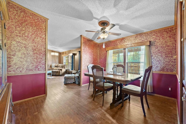 dining space with ceiling fan, wood-type flooring, a textured ceiling, and ornamental molding