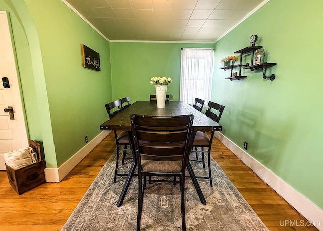 657 Lake Ave, Ironwood, MI 49938 - dining area with ornamental molding, wood finished floors, baseboards, and arched walkways