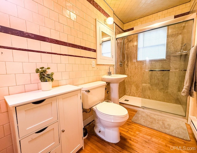 bathroom featuring an enclosed shower, wood-type flooring, tile walls, and toilet