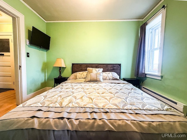 bedroom with a baseboard radiator, hardwood / wood-style flooring, and crown molding