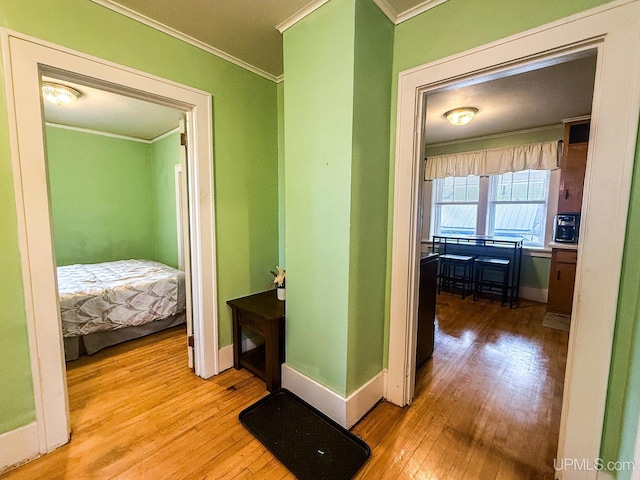 hall with light hardwood / wood-style floors and ornamental molding