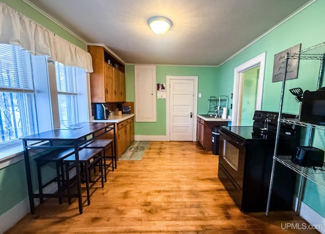 657 Lake Ave, Ironwood, MI 49938 - kitchen with black electric range, crown molding, light wood finished floors, baseboards, and brown cabinetry