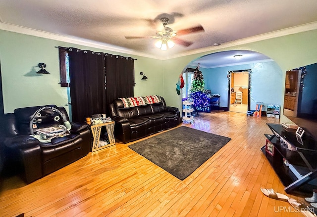 living room with wood-type flooring, a textured ceiling, ceiling fan, and ornamental molding