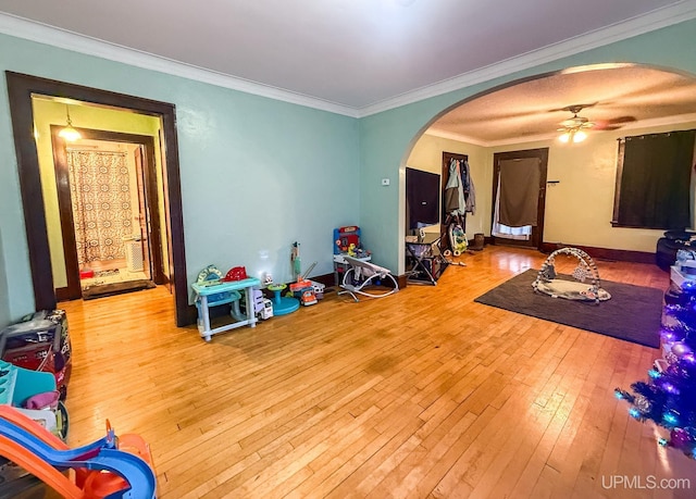 657 Lake Ave, Ironwood, MI 49938 - game room featuring arched walkways, hardwood / wood-style flooring, a ceiling fan, crown molding, and baseboards