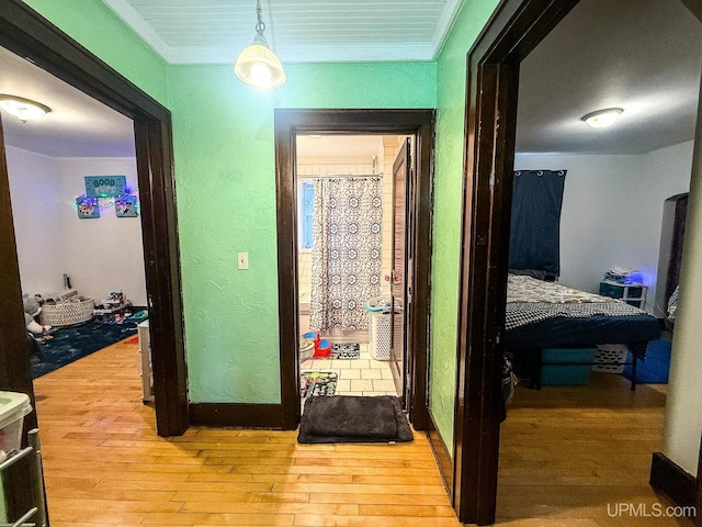 corridor with light hardwood / wood-style flooring and crown molding