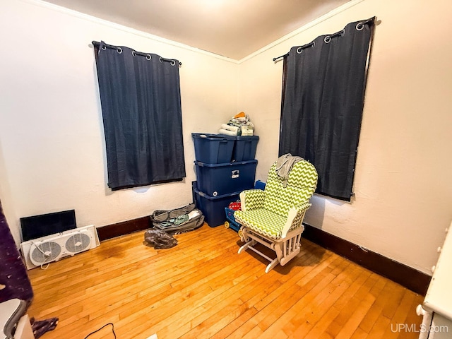 living area featuring wood-type flooring and ornamental molding