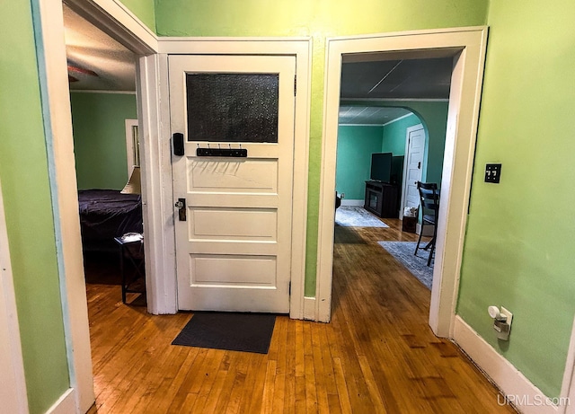657 Lake Ave, Ironwood, MI 49938 - hallway with ornamental molding, hardwood / wood-style flooring, arched walkways, and baseboards