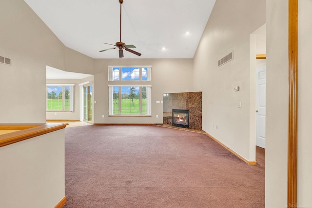 unfurnished living room with carpet flooring, high vaulted ceiling, ceiling fan, and a tiled fireplace