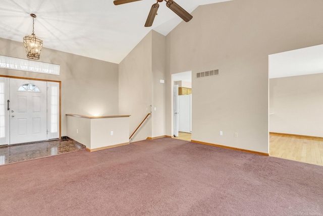 carpeted foyer entrance with ceiling fan with notable chandelier and high vaulted ceiling