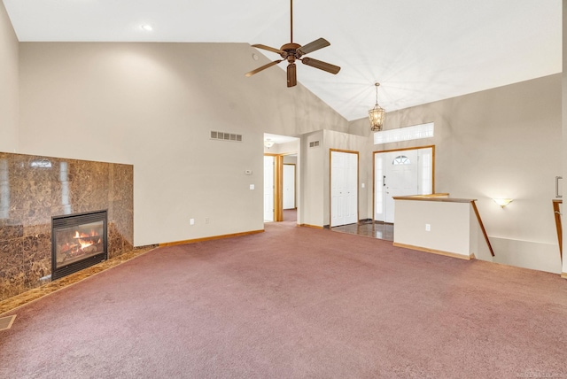 unfurnished living room featuring a tile fireplace, ceiling fan, high vaulted ceiling, and dark colored carpet