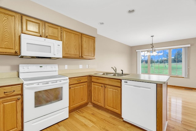 kitchen featuring pendant lighting, white appliances, sink, light hardwood / wood-style flooring, and a notable chandelier