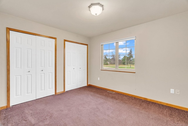 unfurnished bedroom featuring carpet flooring and multiple closets