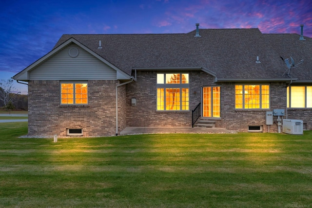 back house at dusk featuring a yard