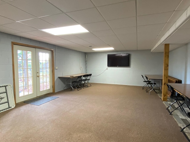 basement featuring french doors, carpet floors, and a drop ceiling