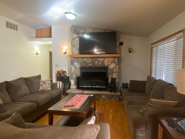 living room with a stone fireplace and wood-type flooring