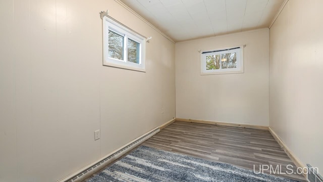 spare room featuring baseboard heating, a wealth of natural light, wood-type flooring, and ornamental molding