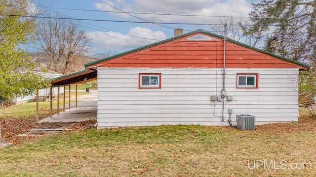 view of side of home with a yard and central AC