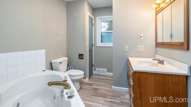 bathroom featuring a tub, hardwood / wood-style floors, vanity, and toilet